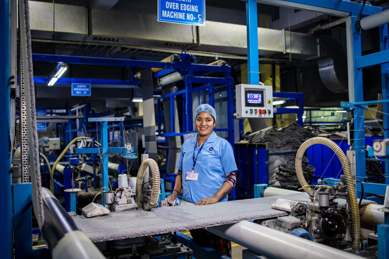 why-choose-us-img Female textile worker operating machinery in a factory, showcasing industrial work environment.